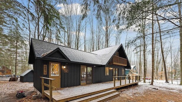 Une cabane dotée d’une terrasse, entourée d’arbres.