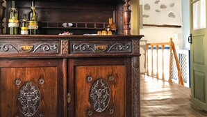 A wooden cabinet with ornate carvings, a glass top, and bottles on the top shelf. - Apartment 'The Balcony Of Bougainvillea' with Sea View, Wi-Fi and Air Conditioning (Ano Syros)