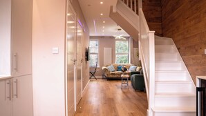 Ein modernes Interieur mit Treppe, Holzboden, einer Couch und einem Essbereich.