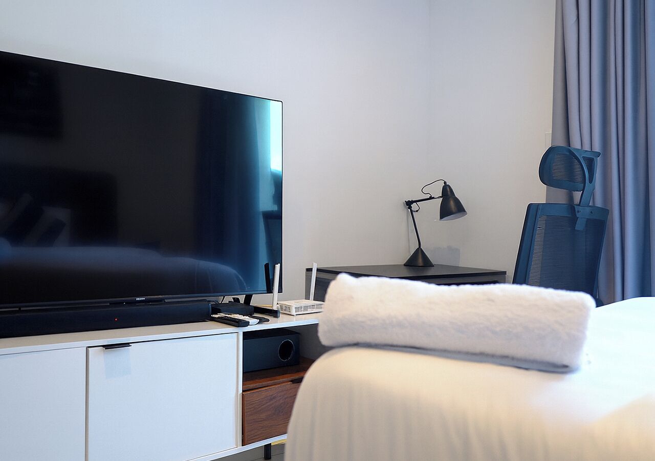 Een hotelkamer met een bed, een televisie, een bureau met een lamp en een stoel.