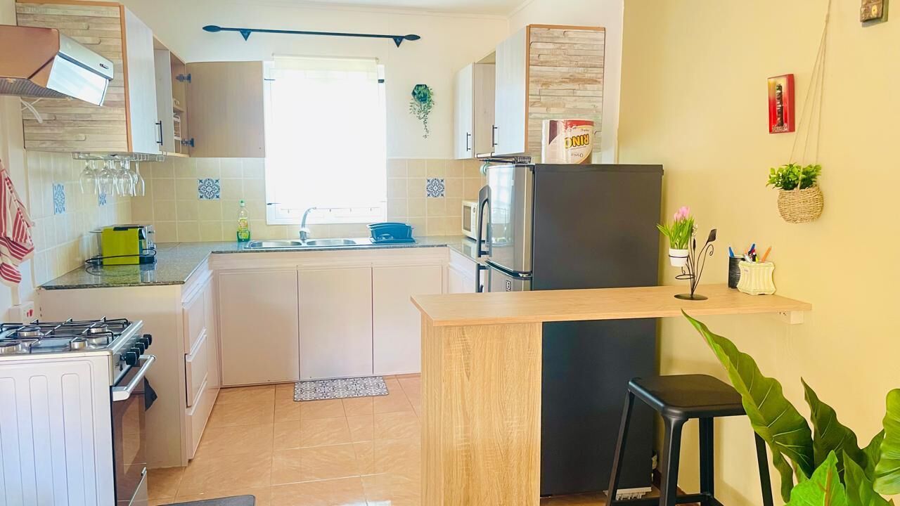 Una cucina con piano cottura a gas, microonde, frigorifero e un piccolo angolo bar.