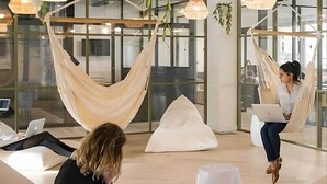 A modern lounge area with seating options including a hammock and bean bags, a large vase, and a laptop on a table. - Student Only Non Ensuite Room Ivy Halls (London)