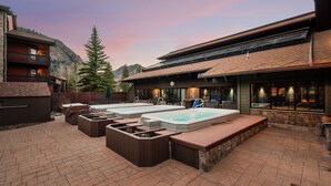 A spa area with hot tubs and outdoor seating, surrounded by stone walls and a mountain backdrop. - New Listing! Walkable Frisco Condo | Near Breck & Copper | Pool + Hot Tub (Frisco)