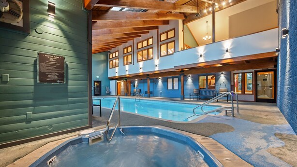 A hot tub area with a pool, wooden beams, and a sign about hot tub rules. - New Listing! Walkable Frisco Condo | Near Breck & Copper | Pool + Hot Tub (Frisco)