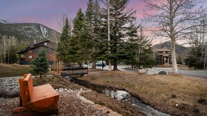 A modern house with a wooden bench, a small stream, and a mountain backdrop. - New Listing! Walkable Frisco Condo | Near Breck & Copper | Pool + Hot Tub (Frisco)