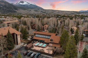 Un hotel con piscina, rodeado de árboles y montañas.
