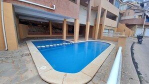 En swimmingpool med en kant av kakel, omgiven av en stenbelagd uteplats.