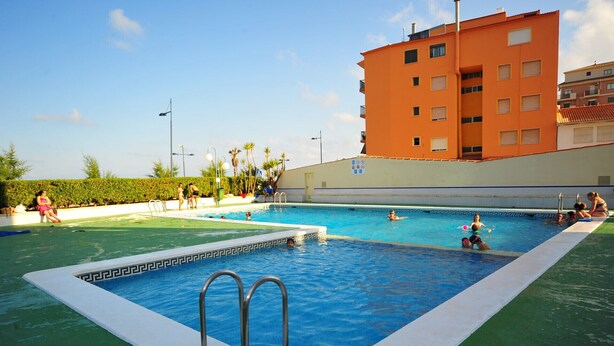 A swimming pool with a white border and a small section with a black and white pattern. There are people in the pool and on the poolside. - EUROPEÑISCOLA SUPERIOR WITH PARKING (Peñiscola)