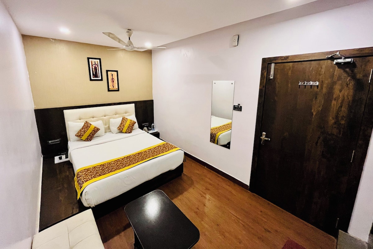 A hotel room with a bed, a bedside table, a mirror, a wardrobe, and a ceiling fan.
