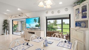 Un comedor con televisor, sillas y vistas a un campo de golf.