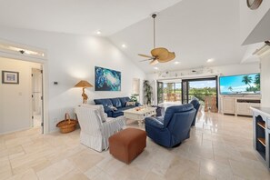 A spacious living area with a sofa, ottoman, and a television. - Seaside Links: Beautiful Home in The Dunes Overlooking the Golf Course (Sanibel)