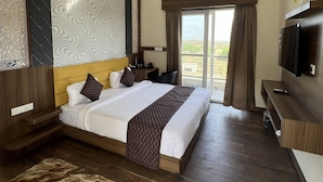A hotel room with a bed, a ceiling fan, an air conditioning unit, a TV, and a view of the outdoors. - Kapish Farms by Kavya International (Udaipur)