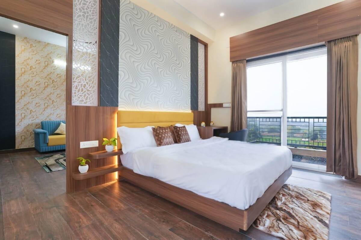 Una habitació d'hotel moderna amb un llit gran, un balcó amb vistes i una cadira blava.