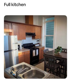 A full kitchen with wooden cabinets, stainless steel appliances, a black stove, and a dining table with chairs. - Walk to river street/enmarket arena… (Savannah)