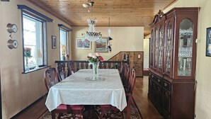Una sala da pranzo con soffitto in legno, un lampadario, un ampio mobile in legno e un tavolo da pranzo con sedie.
