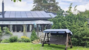 Una casa con tetto solare, patio coperto e panchina in legno.