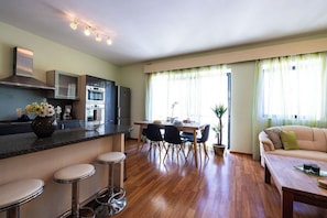 A modern kitchen with a dining area, wooden flooring, and a sofa. - Bright side seaview apartment in Sliema (Qui-Si-Sana), just steps from the promenade. 2 double bedrooms, garage, lift, and central location near cafés, restaurants, and the sea. Perfect for relaxing holidays or longer stays. (Sliema)