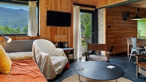 Une pièce confortable avec un canapé, une table et un téléviseur fixé au mur.