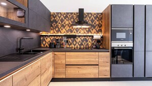 Een moderne keuken met een zwart-bruin betegelde spatwand, een Bosch oven en houten keukenkastjes.