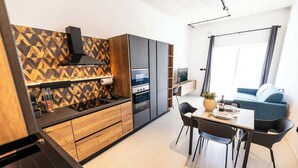 Een moderne keuken met een geometrisch aanrecht, geïntegreerde apparatuur en een eethoek met een tafel en stoelen.