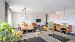 Ein modernes Wohnzimmer mit einem Holzesstisch, einer Couch und einem an der Wand montierten Fernseher.