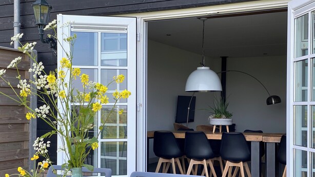 Eine offene Garage mit Essbereich, einem Tisch, Stühlen und einer Hängelampe.