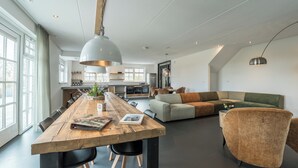 Ein geräumiger Wohnbereich mit einem Holzesstisch, schwarzen Stühlen, einem grünen Sofa und einem braunen Sessel.