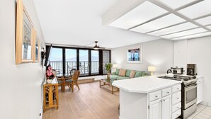 Uma cozinha moderna com ilha central, área de jantar com mesa e cadeiras, e varanda com vista.