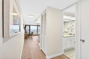 Ein Flur mit Essbereich, ein Schrank mit Klappläden und ein Badezimmer mit weißem Waschbecken und gefliestem Boden.