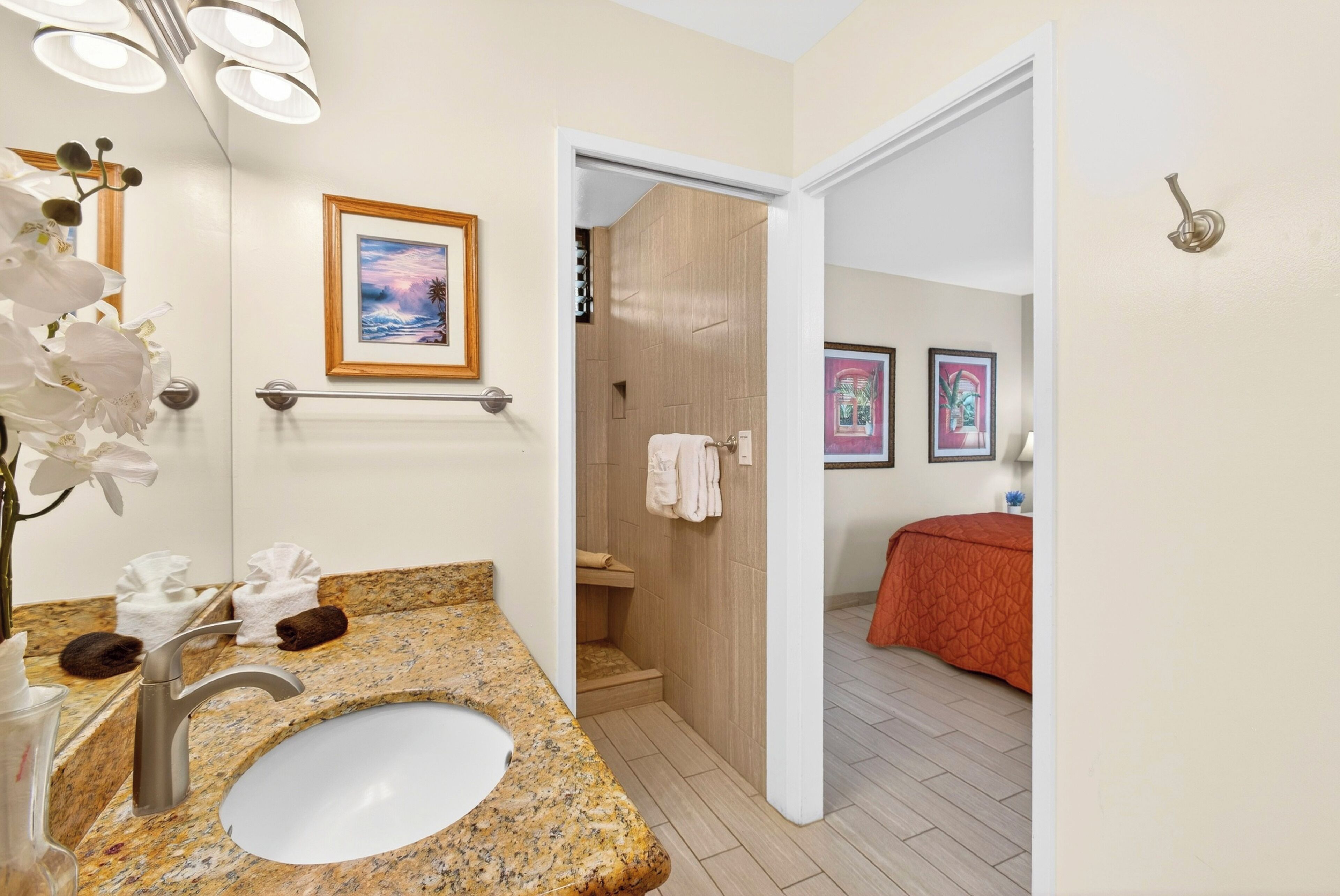 A bathroom with a granite countertop, a sink, a mirror, and a shower area.