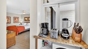 Une chambre d’hôtel équipée d’un lit, d’une machine à café, d’un grille-pain, d’un mixeur et d’un bloc à couteaux posé sur le comptoir.