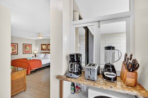Ein Hotelzimmer mit einem Bett, einer Kaffeemaschine, einem Toaster, einem Mixer und einem Schneidebrett auf der Ablagefläche.