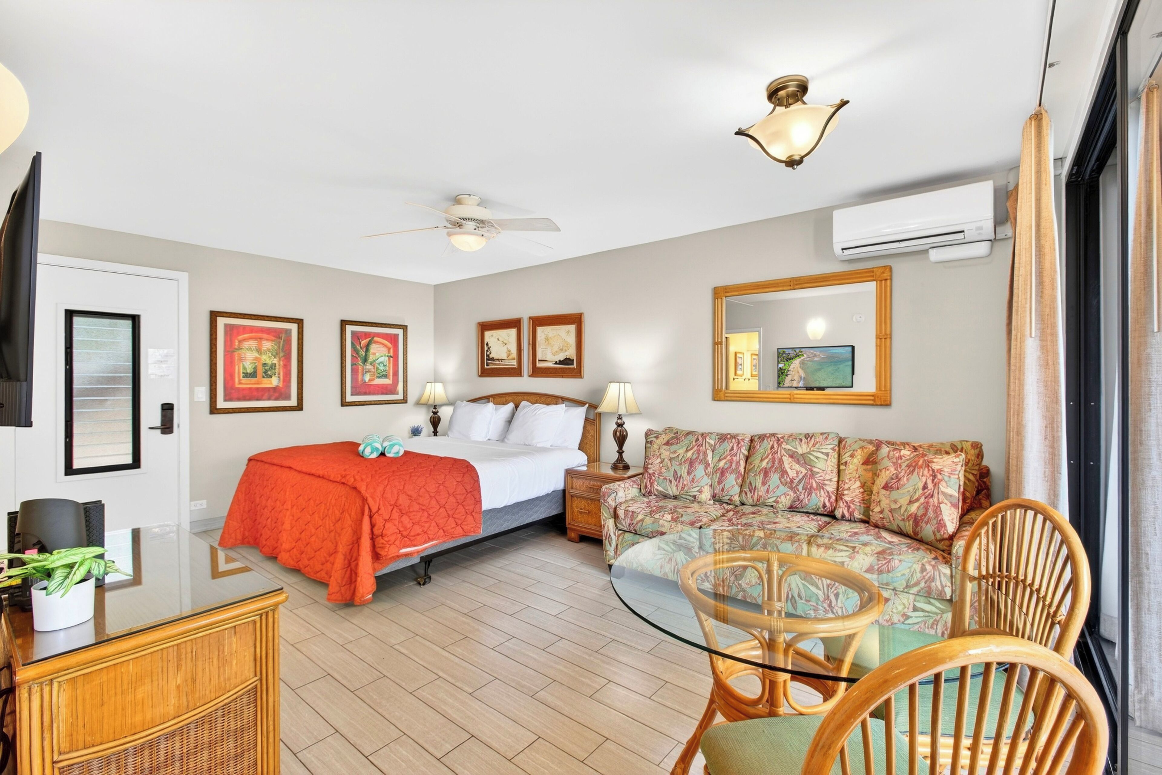 Una habitación de hotel con cama, sofá, mesa de comedor y ventilador de techo.