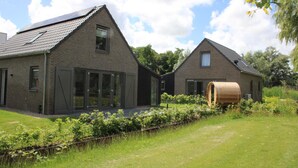 A modern house with a sloped roof, large windows, and a barrel in the garden. - Coastal Home With Sauna for 6 (Sint Maarten)