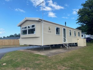 Una casa móvil con un porche delantero, un pequeño garaje adosado y una antena parabólica.