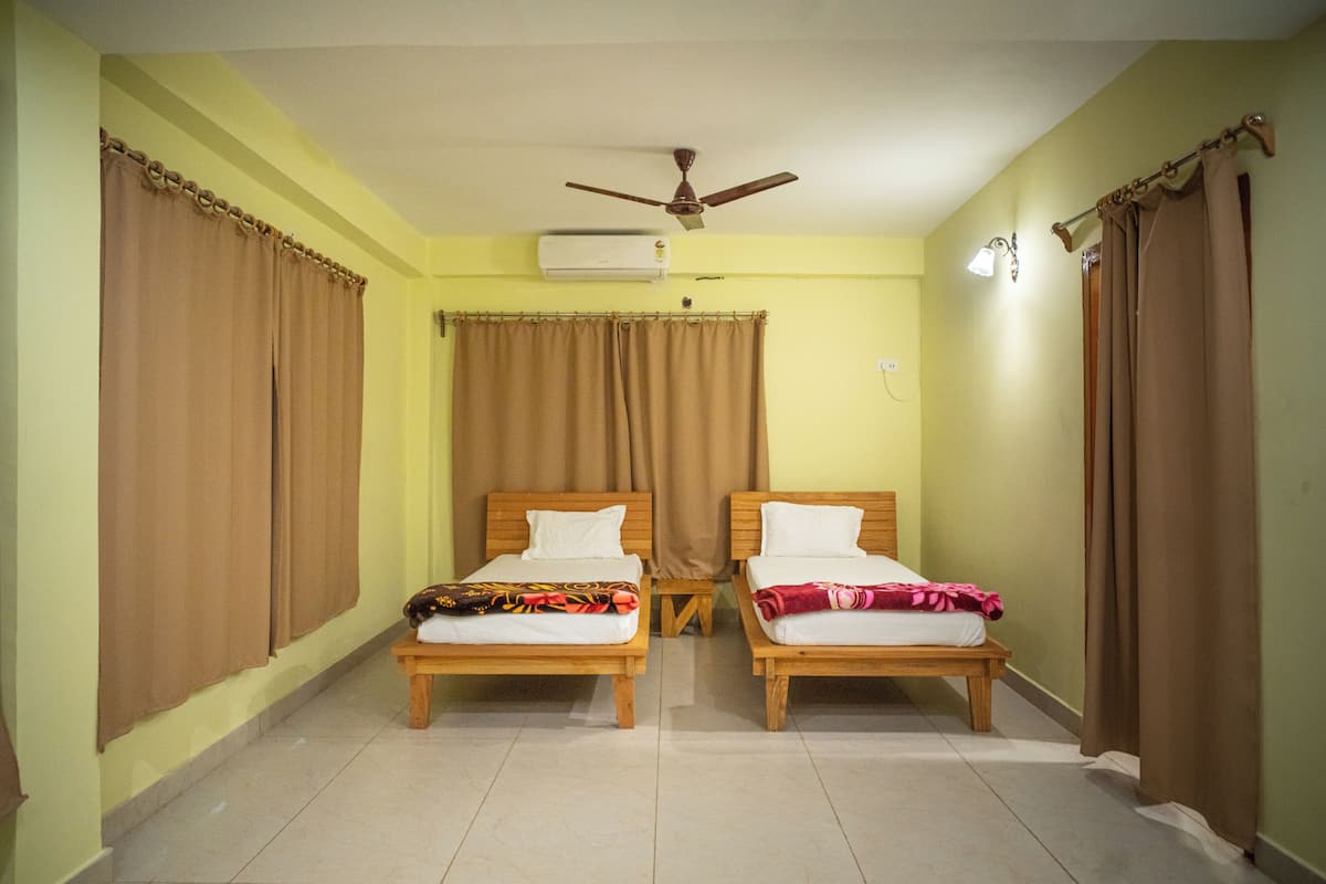 A room with two wooden beds, a ceiling fan, an air conditioner, and curtains.