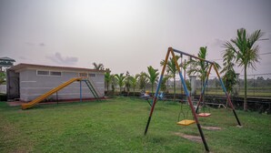 A grassy outdoor area with a swing set and a slide. - Resort Bihanga (Mal)