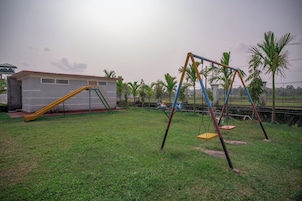 A grassy outdoor area with a swing set and a slide.