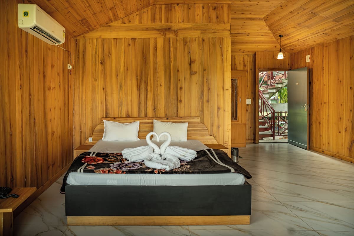 A wooden-paneled room with a bed, a telephone, and an air conditioning unit.