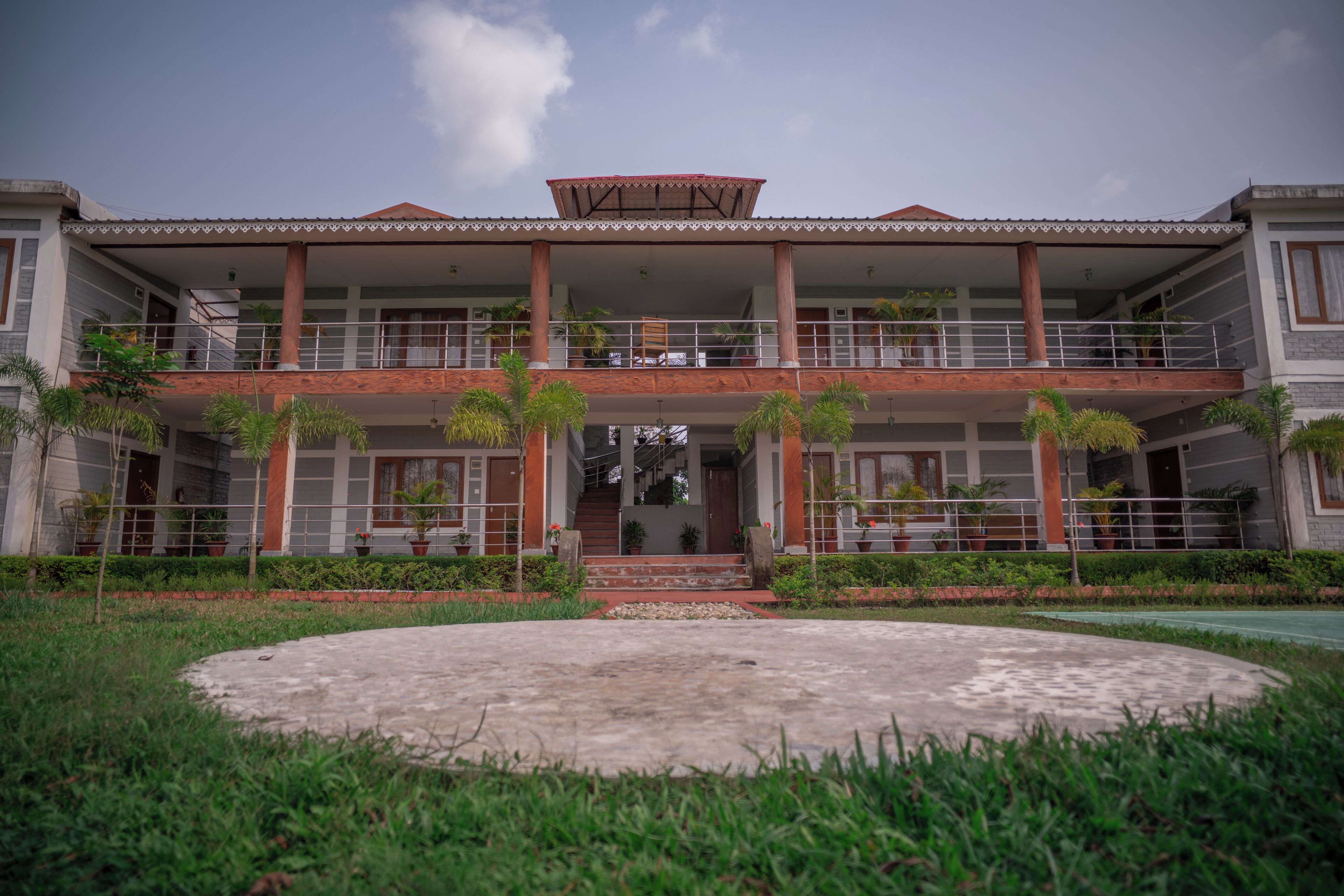 A two-story building with a central staircase, balconies, and a circular driveway.