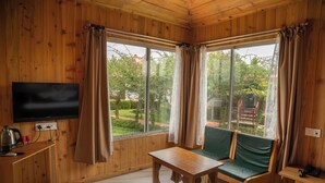 A wooden-paneled room with a television, a table, and a green sofa. - Resort Bihanga (Mal)