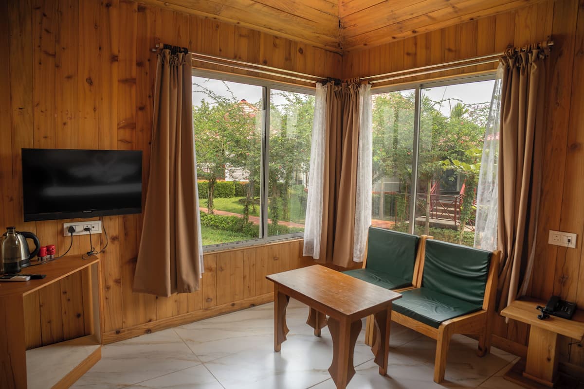 A wooden-paneled room with a television, a table, and a green sofa.