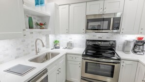 A modern kitchen with white cabinets, a stainless steel stove, a microwave, and a dishwasher. - 112 Arrowhead – Unique Lakefront 2BR at Kingston (Myrtle Beach)