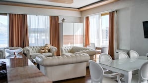 Una sala de estar moderna con un juego de sofá, una mesa de comedor con sillas y un amplio ventanal con cortinas.