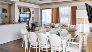 Una sala de estar moderna con un sofá, una mesa de comedor y sillas, un televisor y una pared de piedra.