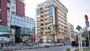Un hotel con fachada de vidrio moderna, una entrada visible y una señal de paso para peatones.