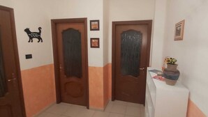A hallway with two wooden doors, a small table with a vase, and a cat silhouette decoration. - Appartamento confortevole con doccia idromassaggio (Torino)
