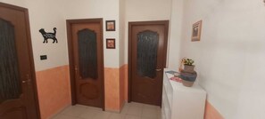 A hallway with two wooden doors, a small table with a vase, and a cat silhouette decoration. - Appartamento confortevole con doccia idromassaggio (Torino)