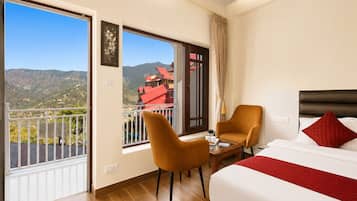 A hotel room with a balcony, a bed, a chair, and a table.