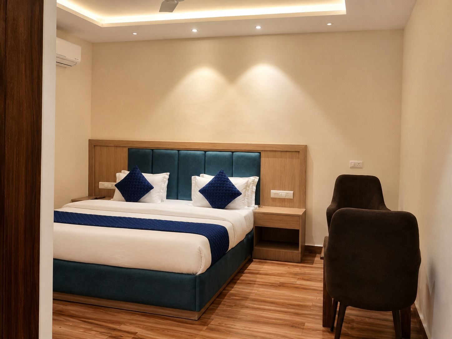 Une chambre d’hôtel moderne équipée d’un lit, de tables de chevet, d’une chaise et d’un luminaire au plafond.